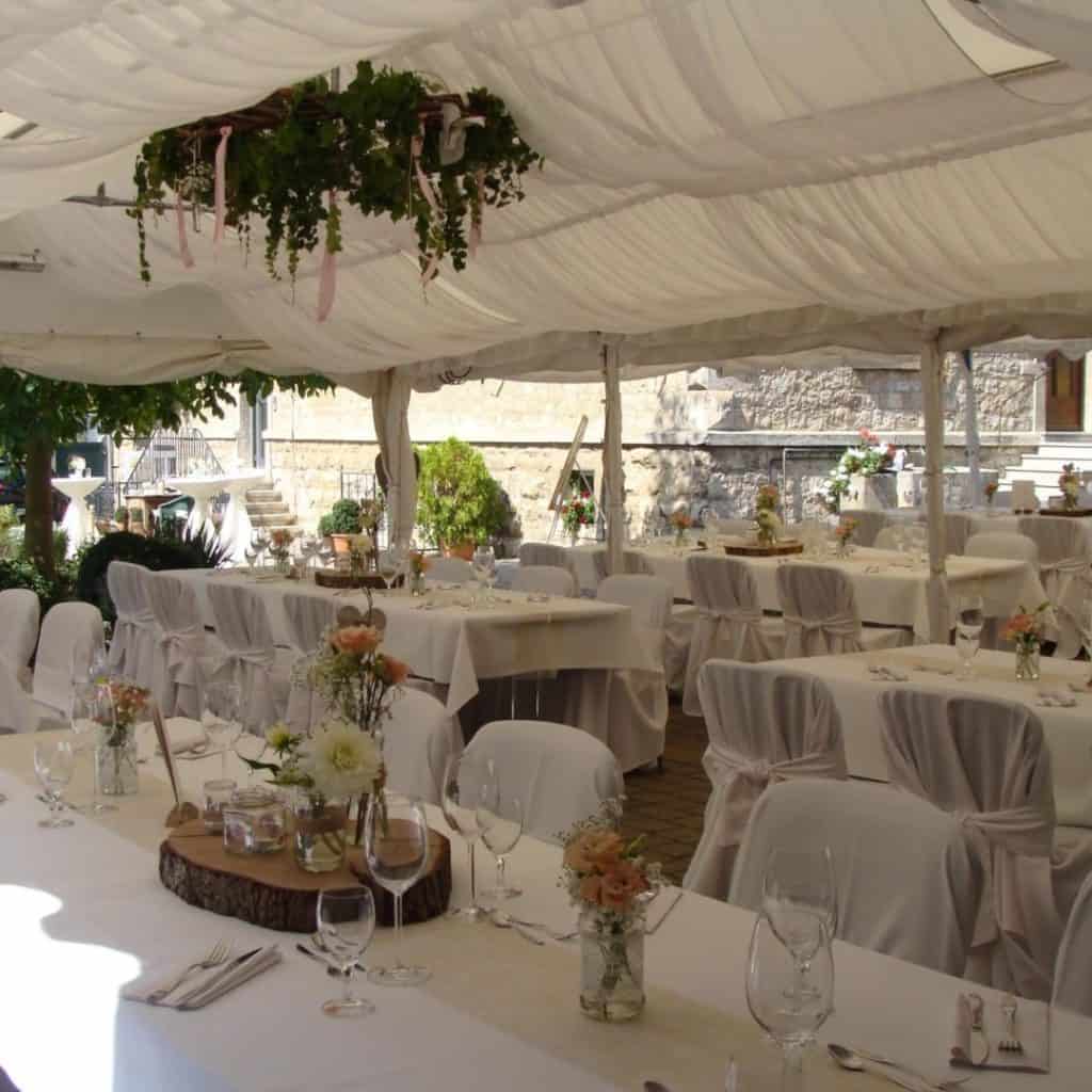 aufgebautes Zelt im Hof mit dekorierten Tischen für die Hochzeitsfeier