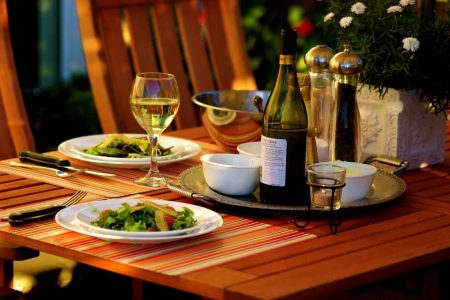 Bistrotisch mit Vorspeisensalat und Flasche Rotwein