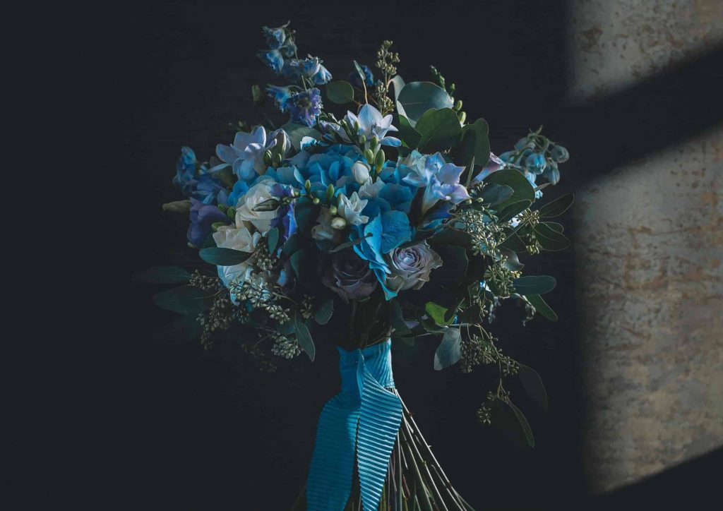 Brautstrauß mit blauen Hortensien, weißen Rosen und Bambus wird von blauem Band zusammengehalten